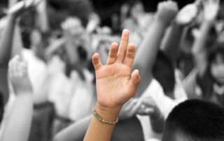 hand in color raised among others hands in black and white background
